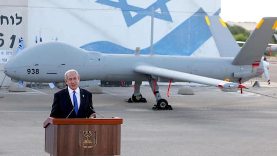Benjamin Netanyahu steht vor einer Drone - Bis heute liefern Schweizer Hersteller militärisch einsetzbare Güter an die Waffenschmiede Elbit Systems, die das Rückgrat der israelischen Kriegsführung ist. Eine Juristin warnt vor einem Völkerrechtsbruch