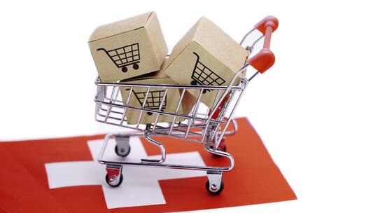 Einkaufswagen mit Paketen steht auf Schweizer Flagge