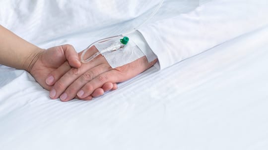 Eine Frau hält die Hand eines Sterbenden.