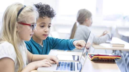 Primarschüler vor einem Laptop - Künstliche Intelligenz und Schule macht vielen Eltern grosse Sorgen. Zwei Expertinnen erklären, wo Gefahren lauern, welches die Chancen sind – und wie Eltern einen klugen Umgang zu Hause fördern können