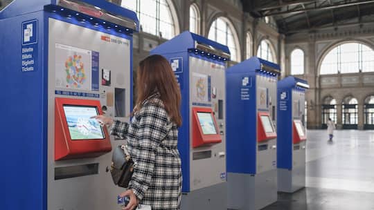 Frau am Billett-Automaten im Bahnhof Zürich - Wer am Automaten die neue Option «Auf Swisspass laden» wählt, sieht danach kein Ticket in der SBB-App. Der Beobachter erklärt, was dahinter steckt – und warum niemand eine Busse fürchten muss