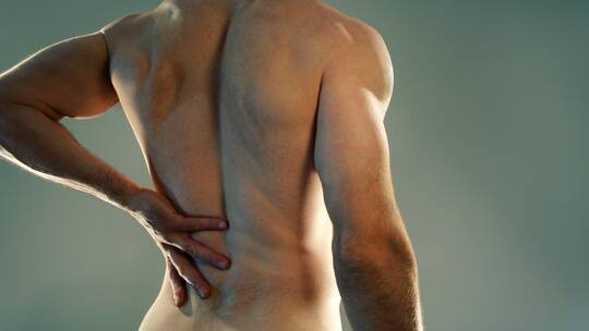 Ein Mann hält sich den schmerzenden Rücken.