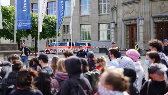Eine gruppe Pro-Palästina Demonstrierende steht vor dem polizeilich gesperrten Eingang der Uni Zürich