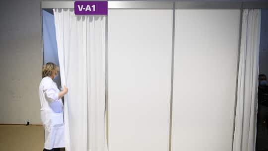 Mitarbeitende blickt in Impfzentrum hinter einen Vorhang