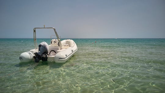 Ein Motorbötli dümpelt im seichten Meer, Blick auf den Horizont