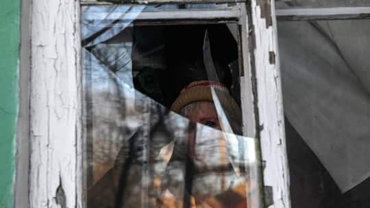 Ukrainekrieg: Frau versteckt hinter zerstörtem Fenster