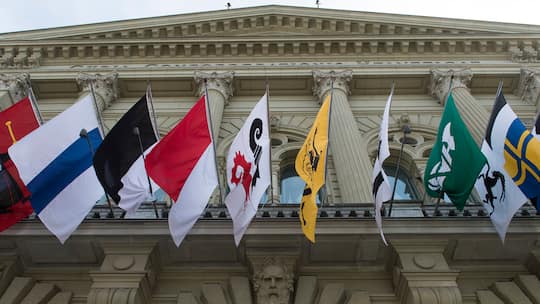 Kantonsflaggen über dem Eingang zum Bundeshaus - Jedes Kind kennt seinen Heimatort, obwohl es oft gar nicht dort wohnt. Dabei hat dieser unterdessen seine wichtigsten Funktionen eingebüsst