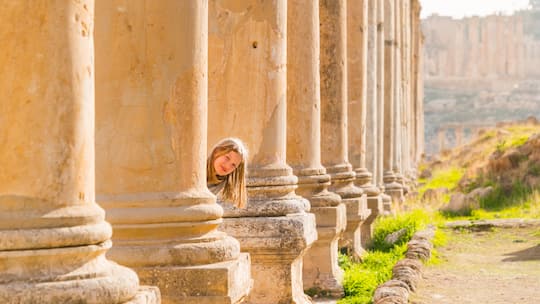 9 years old girl hiding after corinthian columns at Roman city, Jerash, Jordan, Middle East