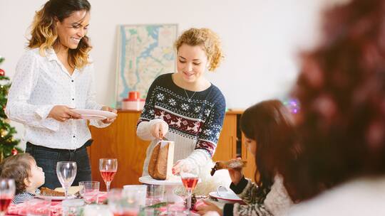 Zwei Frauen verteilen an Weihnachten Kuchenstücke an die Familie.