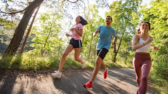 Drei Freunde sind im Wald am Joggen und lachen dabei