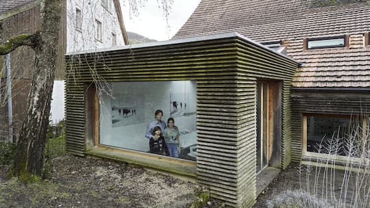 Architekt Christoph Ecker mit seiner Familie im selbst umgebauten Haus in Oltingen. Blick von aussen durchs Fenster in den Anbau.