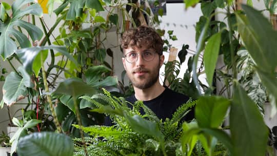Oliver Ingold inmitten zahlreicher Grünpflanzen in seinem WG-Zimmer