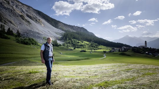 Gemeindepräsident von Brienz, Daniel Albertin, steht auf einer gemähten Wiese, im Hintergrund ist abgerutschtes Geröll erkennbar.