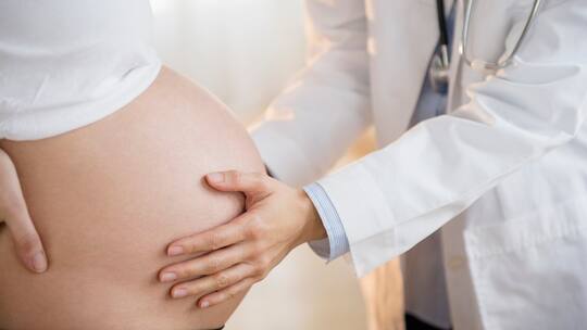 Ärztin untersucht Bauch einer Schwangeren