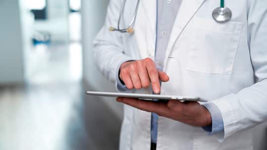 Ein Arzt studiert Patientendaten auf einem Tablet.