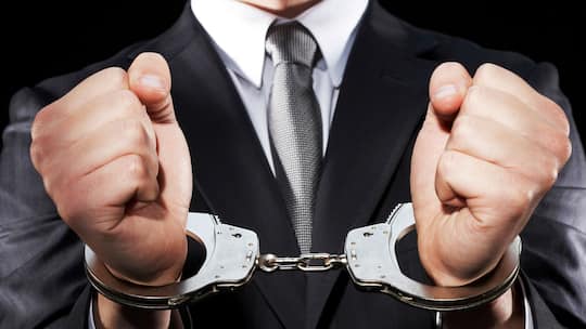 Ein Mann in Anzug trägt Handschellen. Verschaffen Sie sich einen Überblick, wie in der Schweiz ein Strafverfahren generell abläuft.