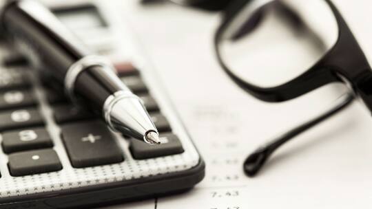 Ein Taschenrechner liegt auf einem Papier mit Notizen und Zahlen drauf.