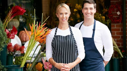 Ein Ehepaar, das einen Blumenladen führt, steht gemeinsam vor ihrem Geschäft.