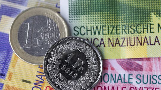 Euro- und Frankenmünze auf Schweizer Banknoten - Reisen in die Eurozone bleiben für Schweizerinnen und Schweizer 2026 erschwinglich. In Ländern wie Frankreich oder Norwegen sind Ferien sogar günstiger geworden