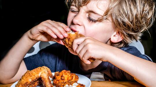 Ein Junge isst Poulet - Manches Essen weckt Erinnerungen und sorgt für gute Laune. Es lohnt sich also, darauf zu achten, was auf den Teller kommt