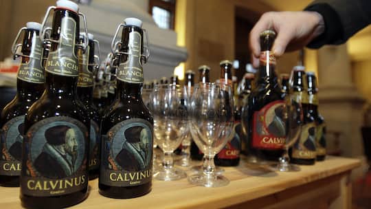 Une personne dispose une biere Calvinus brassee par les freres Papinot artisans brasseurs de Geneve, lors de l'exposition des illustrations du Calvindrier, ce jeudi 15 janvier 2009 a Geneve. A l'occasion du Jubile Calvin, 500e anniversaire de la nais…