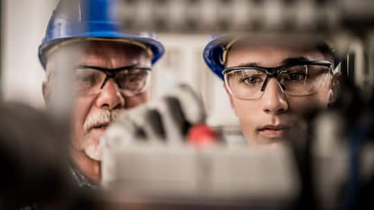 Close up of male apprentice connecting the wires in the distribution board under supervision of a senior electrician.
1218721877