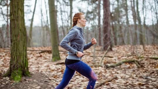 Side view of determined woman jogging in forest