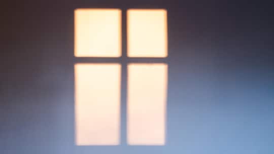 Shade of a window on a white wall with sunset light