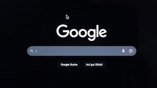 Ein Computerbildschirm zeigt die Startseite der Suchmaschine Google im dunklen Modus mit sichtbarem Mauszeiger. Google-Startseite auf einem Computerbildschirm. Symbolbild zur Illustration von Internetdiensten, Suchmaschinen oder digitaler Recherche. …