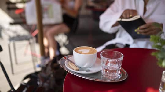 Ein Cappuccino, zubereitet mit Haferdrink, steht auf einem Tisch eines Cafés.