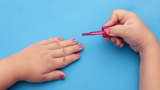 2AH2E5D children's manicure. Children's hands paint their nails with Colorful nail polish. Red manicure on childish nails.