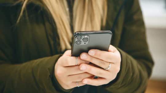 The girl uses a cell phone with a triple camera.