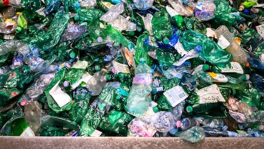 A large collection of plastic bottles is ready for the recycling process featuring various colors and labels. The bottles are gathered in a facility dedicated to waste management and environmental sustainability.