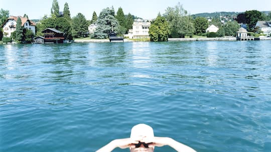 Eine junge Frau mit Badekappe und Sonnenbrille haelt von einem Schiff aus Ausschau, aufgenommen im Sommer 2006 vor der "Goldkueste" im Kanton Zuerich. (Stefan Jaeggi by KEYSTONE)
SCHWEIZ SOMMER