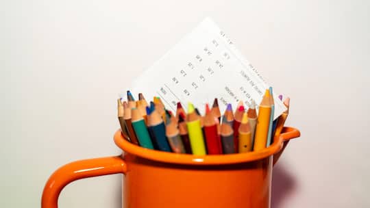 Invoice in an orange jar of colored pencils on white background with copy space