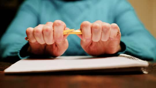 Nahaufnahme der Hände eines Schülers, der einen Bleistift zerbricht.