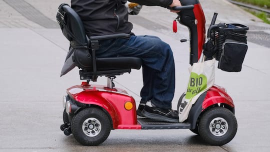 Ein Senior fährt auf einem roten Elektromobil