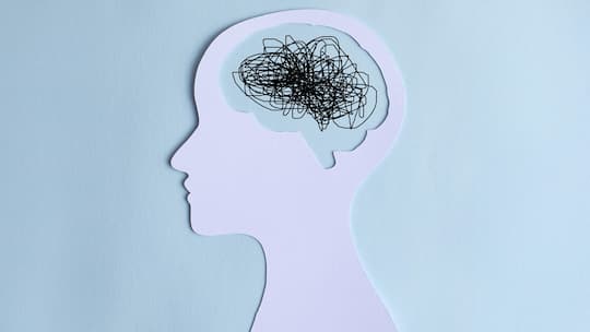 Paper cut out of a human head with a chaotic line drawing for a brain. Burn out or mental overload Concept