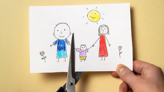 2GA54X9 Child's drawing, which depicts mom, dad and child, is cut with scissors.