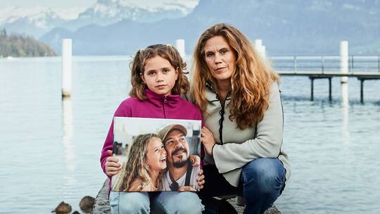 Andrea Huber mit ihrer Tochter Malena, die ein Foto mit dem verstorbenen Vater hält