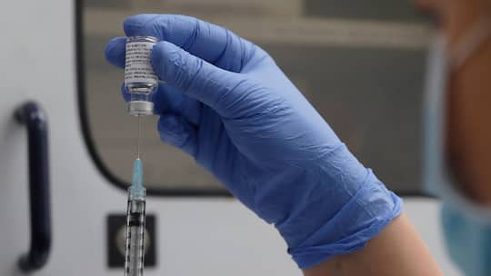 Mann zieht Spritze mit einer Dosis des Impfstoffs von Novavax auf