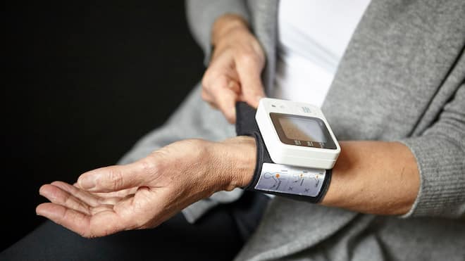 Welche Blutdruckmessgeräte zuverlässig sind Eine Frau befestigt ein Blutdruckmessgerät am Handgelenk.