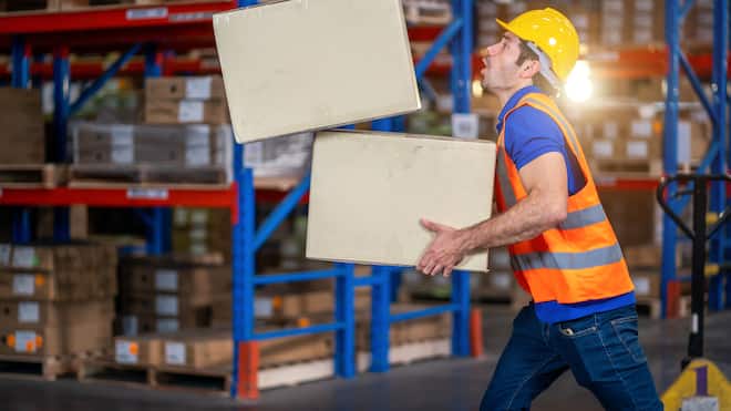 Zahlen Angestellte für ihre Fehler? Ein Mitarbeiter einer Lagerhalle gerät ins Stolpern. Dabei fällt eine von zwei Schachtel zu Boden, die der Mitarbeiter beim Umfallen nicht mehr festhalten kann.