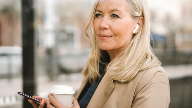 Mit Genuss gegen die Widrigkeiten des Alltags Entspannte Frau wartet an Bushaltestelle