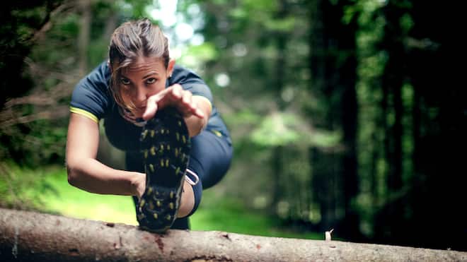 Die zehn grössten Fitness-Irrtümer Eine Frau dehnt sich nach dem Joggen im Wald.