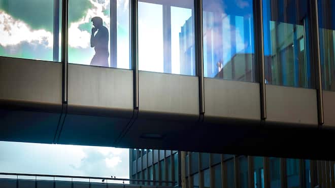 Ein Plädoyer gegen die Vereinzelung Mann am Smartphone geht alleine durch Bürogang