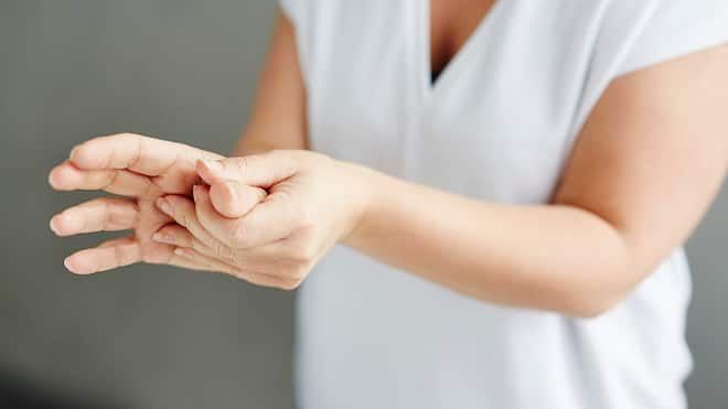 Schmerzen bis an die Grenzen Eine Frau reibt sich die schmerzende Hand.