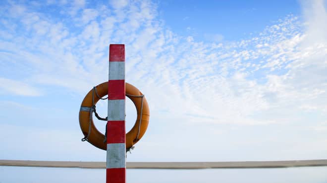 Wer zahlt die Annullierungskosten? Bild eines Rettungsrings am Strand.