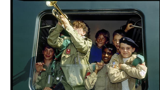 Von Piraten, Lagerfeuern und Mutproben Eine Gruppe Pfadfinder schaut aus einem Zugfenster, einer bläst eine Trompete