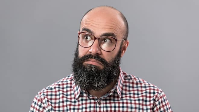 Was bei Haarausfall hilft Ein Mann mit Glatze schaut skeptisch nach oben.